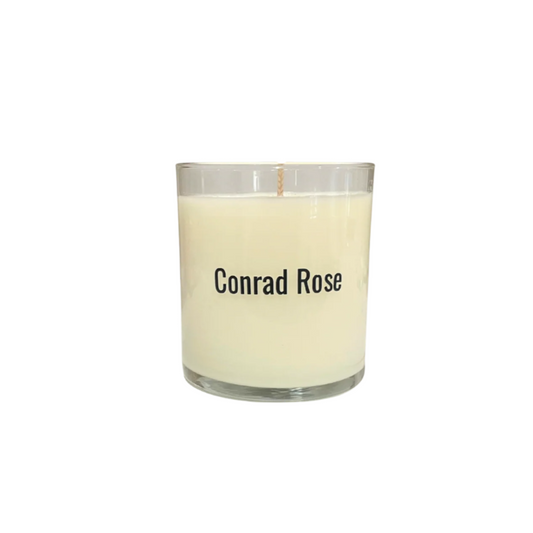 Candle in a glass jar with 'Conrad Rose' branding on a white background