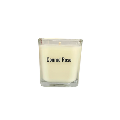 Glass candle with 'Conrad Rose' branding on a white background