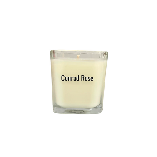 Glass candle with 'Conrad Rose' branding on a white background